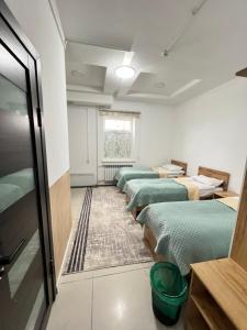 a row of beds in a room with a window at Sayak hotel & hostel in Karakol