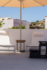 a patio with two chairs and a table and an umbrella at CASA Terraya in Afantou