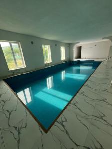 a large swimming pool with blue water in a room at Hotel Villa DavidL in Sagarejo