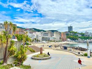a city with a beach and buildings and palm trees at マリーナベイCentral in Atami