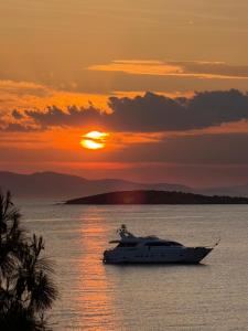 a boat in the water with the sunset in the background at PJ Properties Sunset Residence Sounio in Sounio