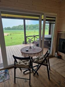 a table and chairs on a porch with a view of a field at Medsukys - Namukai Dviem in Griniūnai