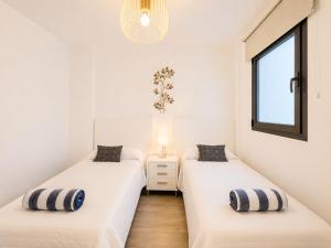 two beds in a room with white walls and a window at Arguineguin Sun Beach in Arguineguín +4 photos