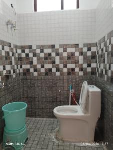 a bathroom with a toilet in a tiled room at Kunjapuri Homestay in Uttarkāshi