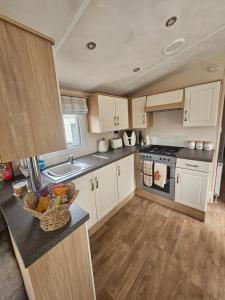 a kitchen with white cabinets and a bowl of fruit on a counter at LuLu's Lodge, Billing Aquadrome in Northampton
