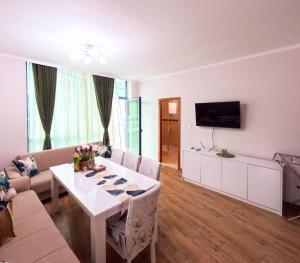 a living room with a white table and a tv at Sunny Cozy Apartment Primorsko in Primorsko