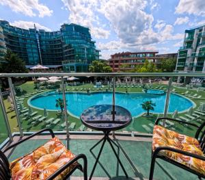 a balcony with a table and chairs and a pool at Sunny Cozy Apartment Primorsko in Primorsko