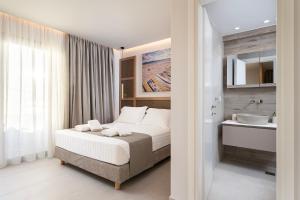 a bedroom with a bed and a bathroom with a sink at Elysian Beachfront Luxury Suite with Jacuzzi - Sea & City View - ADULTS ONLY in Kos