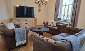 a living room with leather furniture and a flat screen tv at Holiday Apartment Henry - Auszeit unter alten Balken in Arnstadt