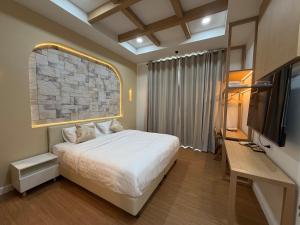 a bedroom with a bed and a flat screen tv at The Verona pool villa Hatyai in Ban Khlong Pleo +10 photos