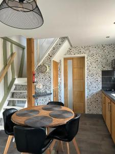 a dining room with a wooden table and black chairs at La maisonnette in Forêt-la-Folie