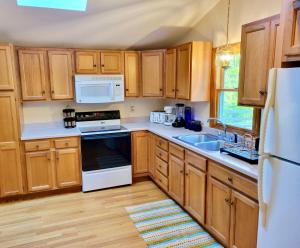 a kitchen with wooden cabinets and white appliances at The Suite at Liberty Woods in Belchertown