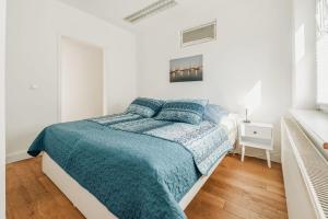 a white bedroom with a bed with a blue comforter at Haus Teltow in Teltow