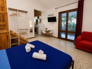 a room with a blue bed and a red couch at Il Giardino su Lido Burrone in Favignana