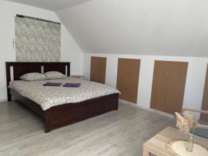a bedroom with a bed with purple pillows and a table at Viesu nams Purenes in Vecmuiža
