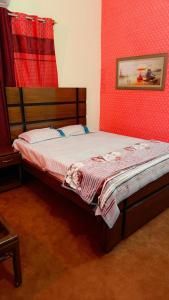a bedroom with a bed with a red wall at Prime Stay in Multan