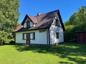 a small white house with a brown roof at Viesu nams Purenes in Vecmuiža