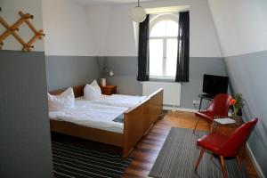 a bedroom with a bed and a window and red chairs at Gut Boltenhof in Fürstenberg