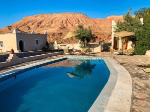 a swimming pool with a mountain in the background at Dar Bikouch in Aït Benhaddou