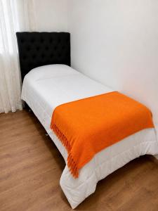 a bed with an orange blanket on top of it at Cavalheris House - Rota das Vinícolas in Espirito Santo Do Pinhal