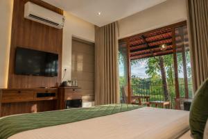 a bedroom with a bed and a television and a balcony at Athirapilly Fernvalley Resort in Athirappilly