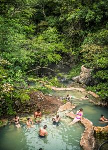 people are swimming in the water at Hacienda Guachipelin Volcano Ranch Hotel & Hot Springs in Liberia