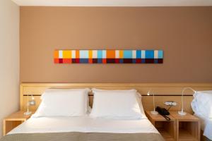 a bedroom with a bed with a colorful painting on the wall at Hotel La Pergola Dependance in Lignano Sabbiadoro