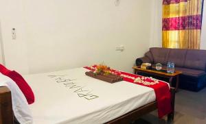 a room with a bed with a couch and a table at Grand Bay Hotel in Arugam Bay