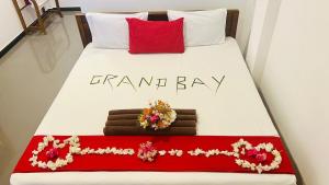 a white bed with red pillows and flowers on it at Grand Bay Hotel in Arugam Bay