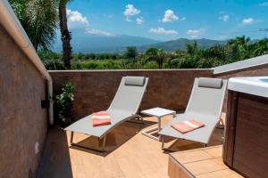 two chairs and a table on a balcony with a mountain at Villa Angheli in Giardini Naxos