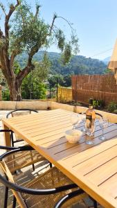 a wooden table with a bottle and glasses on it at Maison Aqua Bella - Terrasse - BBQ - 8pers in Contes