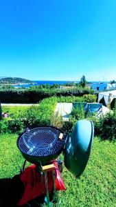 a grill and a chair sitting on the grass at Villa Infinity View Athens Riviera in Anavyssos