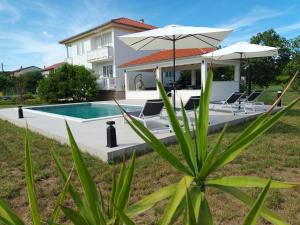 a villa with a swimming pool and two umbrellas at Apartman Blaženka in Kampor