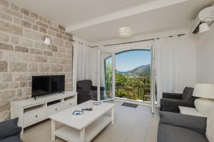 a living room with a couch and a tv at Lavender house with shared pool in Herceg-Novi