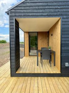a black shed with a table on a wooden deck at Feriebyens Spahuse in Rødvig +5 photos