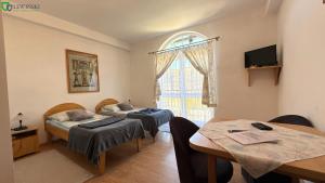 a room with two beds and a table and a window at Dworek Słoneczko in Smołdzino