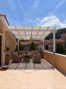 a patio with a white pergola on a house at green & blue villa in Glykadi