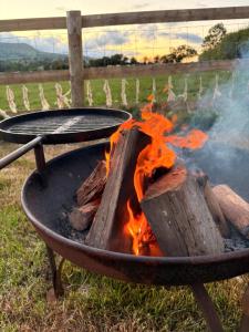 a bbq grill with fire in a field at Hedgerow hideaway in Llanvetherine