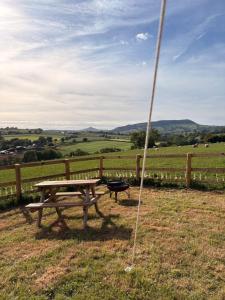 a picnic table in a field with a fence at Hedgerow hideaway in Llanvetherine +7 photos