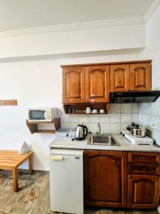 a kitchen with wooden cabinets and a sink at Anna Garden Sidari in Sidari