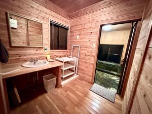 a bathroom with a sink in a wooden cabin at Lodge Kurokawa 2 Forest in Minamioguni +10 photos