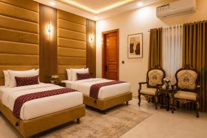 a hotel room with two beds and a chair at City rooms in Karachi