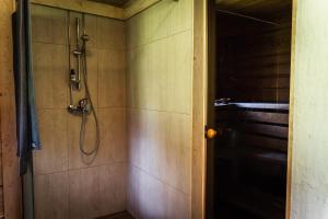 a bathroom with a shower with a hose on the wall at Sauna house with minilake in Voki +26 photos