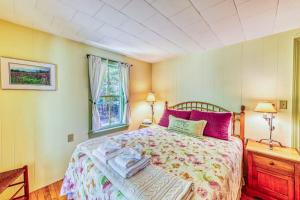 a bedroom with a bed with pink pillows and a window at Gingerbread Cottage in Sugar Hill
