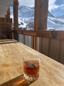 a glass of whiskey sitting on a table on a balcony at Les Appartements de Maé in Val Thorens