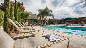 a swimming pool with lounge chairs and a table at Days Inn & Suites by Wyndham Lodi in Lodi