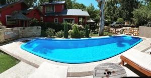 a large blue swimming pool in front of a house at Complejo del jaguel Reserva del Bosque in Santa Teresita