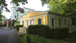 a small yellow house with a white lighthouse behind it at Apartment v podzámčí in Františkovy Lázně