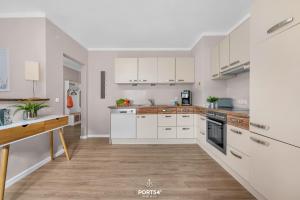 a kitchen with white cabinets and a wooden floor at Ferienwohnung Windjammer 5 St Peter-Ording in Sankt Peter-Ording