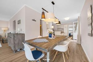 a dining room with a wooden table and white chairs at Ferienwohnung Windjammer 5 St Peter-Ording in Sankt Peter-Ording